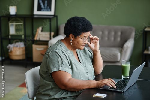 Side view portrait of black senior woman using laptop for online shopping, copy space photo