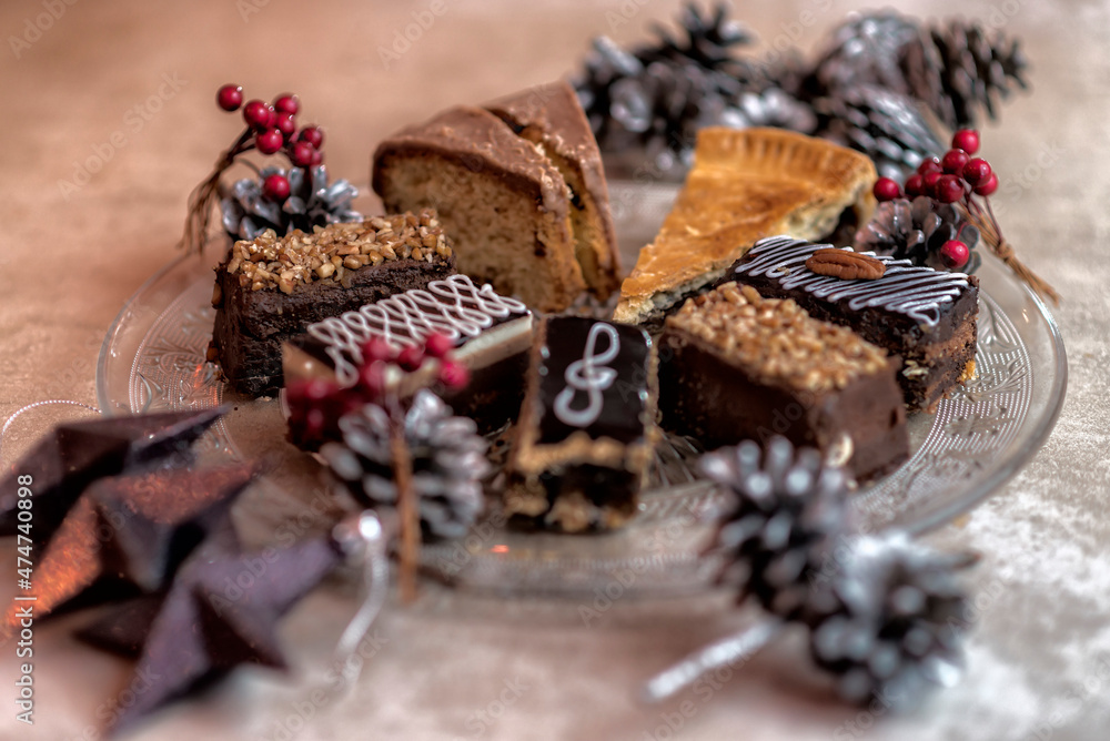 Variety of desserts chocolate coffee cake brownie apple pie on a glass plate with pine cones and berries christmas decoration Variety of desserts chocolate coffee cake brownie apple pie on a glass plate with pine cones and berries christmas decoration
