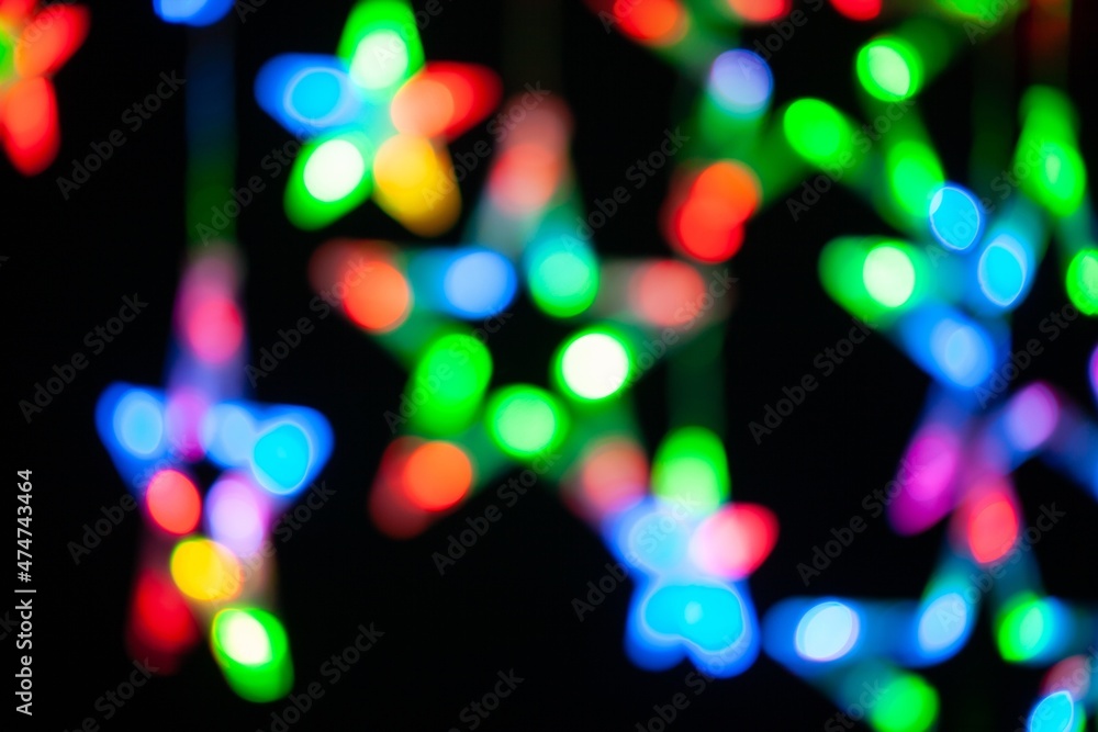 Naklejka premium Abstract Glowing light bulb garland star-shaped Christmas lights on black background.