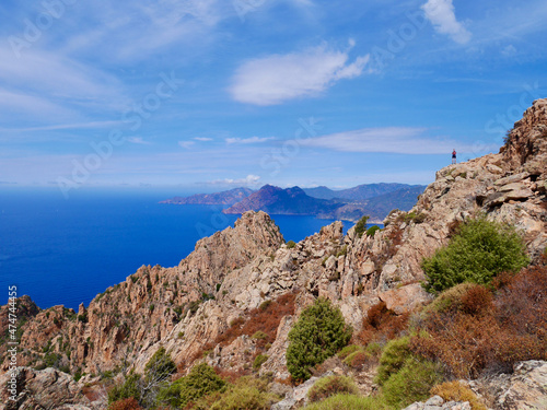 Man looking at the red cliffs of the Calanche, UNESCO world heritage, and the Golf of Porto. Corsica, France. © Maleo Photography