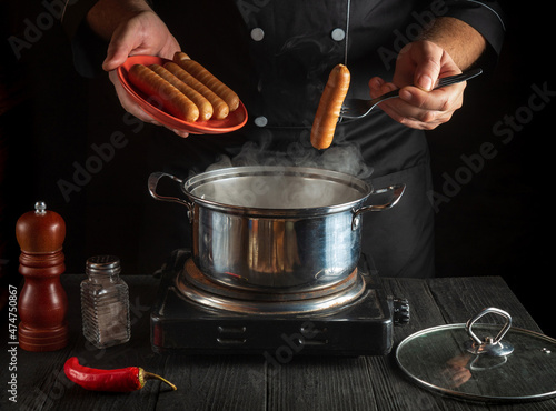 Professional chef puts Vienna sausage in a saucepan. Working environment in the kitchen of a restaurant or cafe. Preparing breakfast or lunch photo