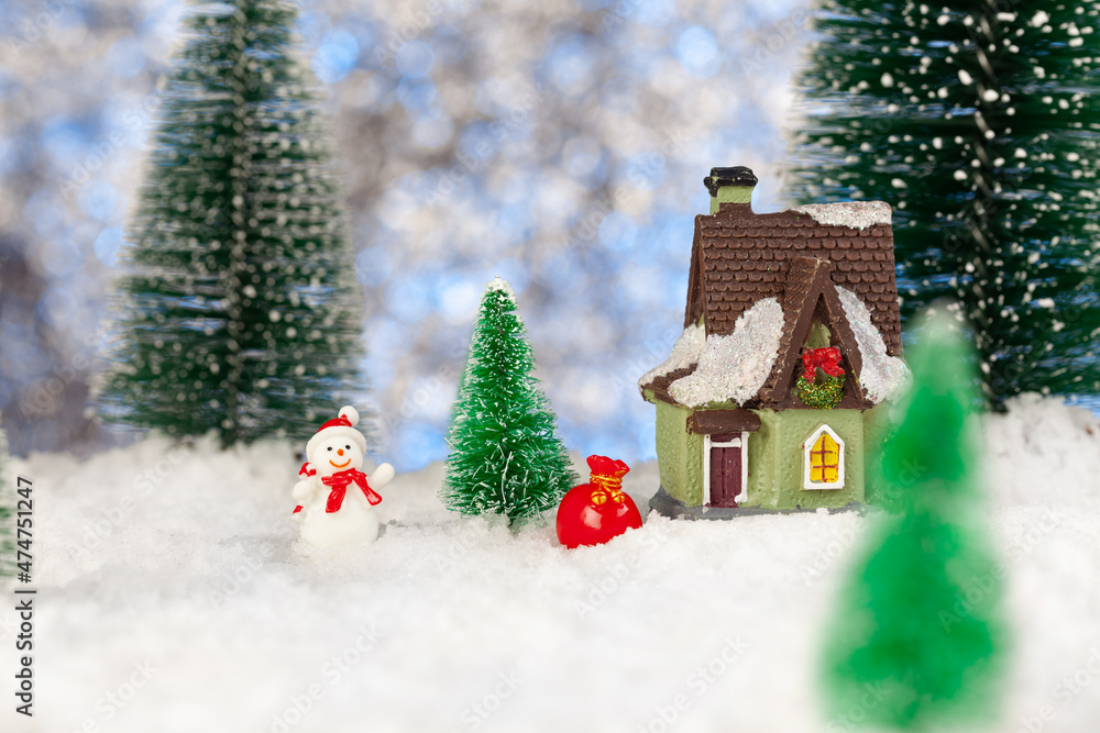 toy snowman with a bag of gifts near a small house, christmas greeting card