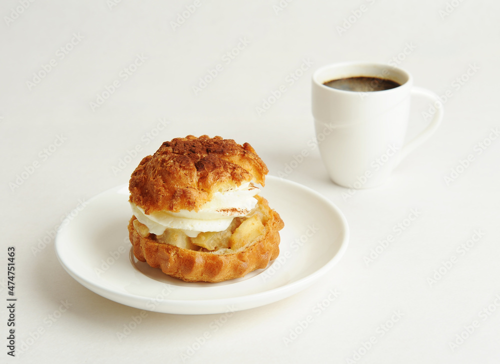 Shu cake dessert with cream on a white plate and a cup of coffee. White background Shu cake dessert with cream on a white plate and a cup of coffee. White background