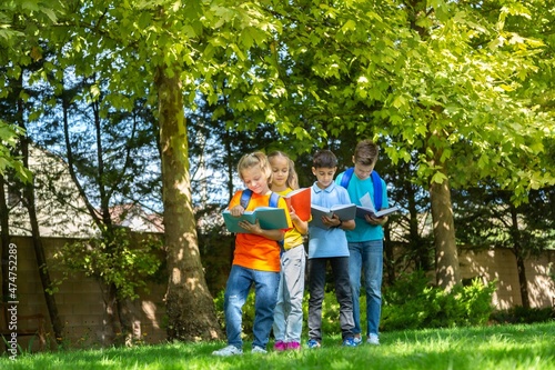 Group of happy school child with book in outdoor park