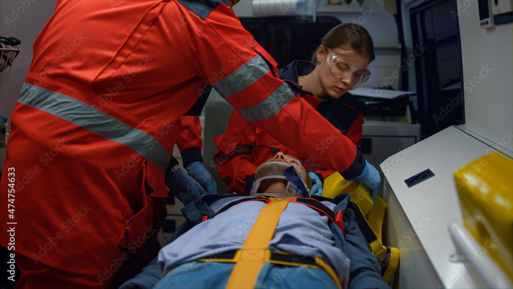 Mixed race paramedics taking care about patient in emergency vehicle Mixed race paramedics taking care about patient in emergency vehicle