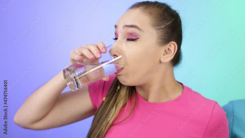 The girl drinks water from a glass. The girl drinks water from a glass.