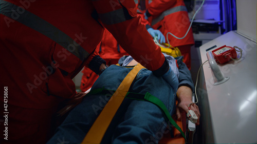 Paramedics giving first aid to patient in ambulance car. Doctor examining man 