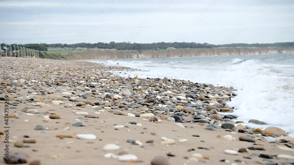 Surf slowly washing over pebbles on a beach Surf slowly washing over pebbles on a beach