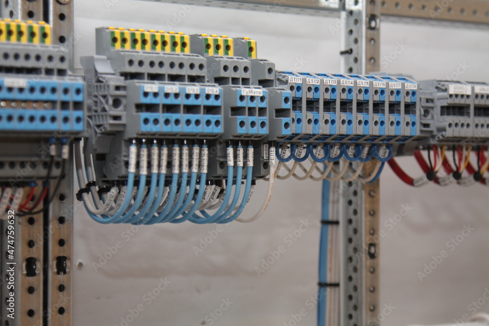 The electrical terminals are connected by a colored wire and mounted on a din rail in the electrical panel.