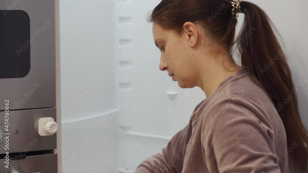 Woman cleaning refrigerator in the kitchen at home. Integrated refrigerator built into the white kitchen housing, contemporary apartment interior. High quality 4k footage Woman cleaning refrigerator in the kitchen at home. Integrated refrigerator built into the white kitchen housing, contemporary apartment interior. High quality 4k footage