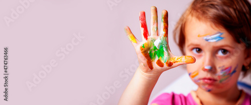 Cute beautiful child girl with colorful painted hands. Horizontal image. Selective focus on hand. Copy space.