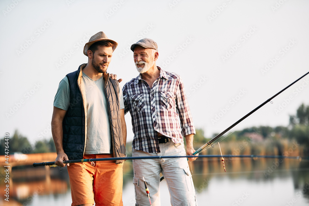 Happy senior man talks to his son after fishing on river in nature. Happy senior man talks to his son after fishing on river in nature.