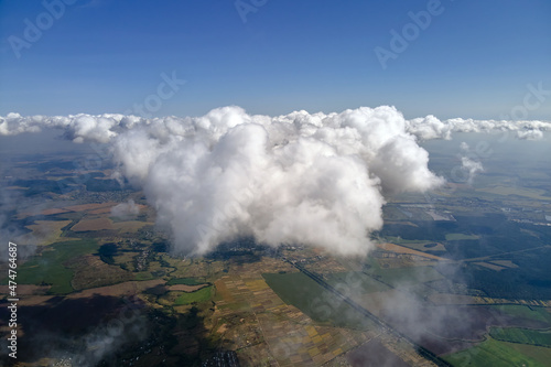 Aerial view from airplane window at high altitude of earth covered with white puffy cumulus clouds