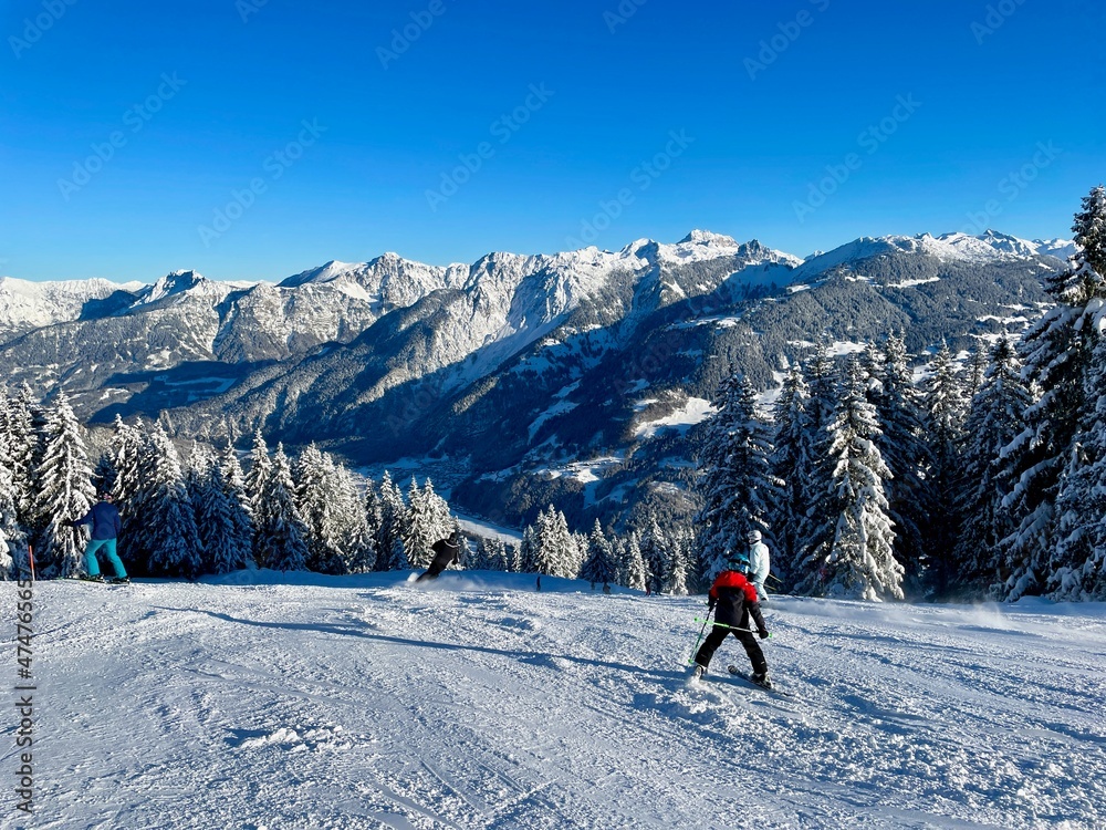 Skiers in the Austrian Alps on a sunny winter day, breathtaking panoramic view of snow-covered mountains.