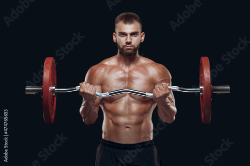 Front view of a strong man bodybuilder exercising with a barbell isolated on black background