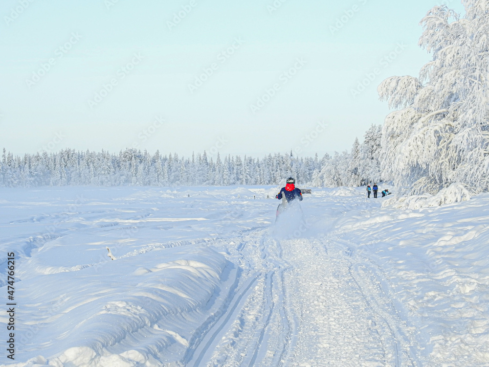 Ein Schneemobilfahrer von hinten fährt durch den Schnee in Lappland Finnland
