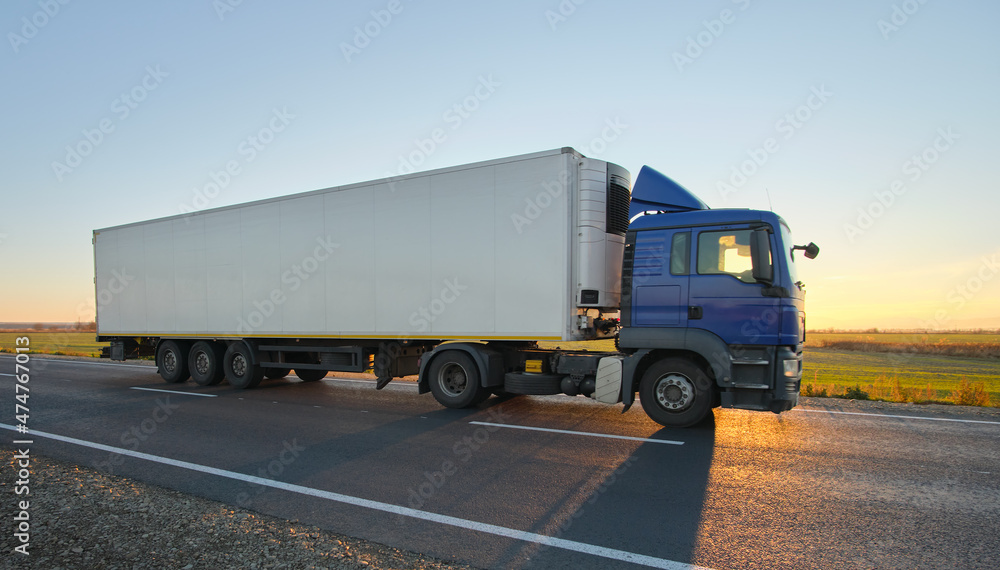 Semi-truck with cargo trailer driving on highway hauling goods in evening. Delivery transportation and logistics concept Semi-truck with cargo trailer driving on highway hauling goods in evening. Delivery transportation and logistics concept