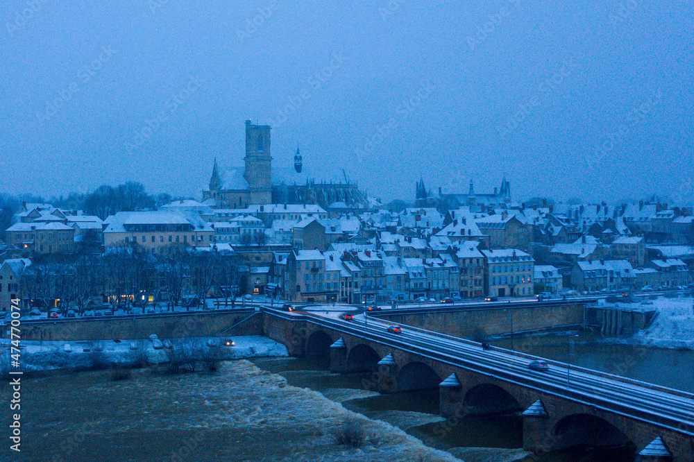 The Loire bridge in Nevers under the snow in Europe, France, Burgundy, Nievre, in Winter, on a cloudy evening.