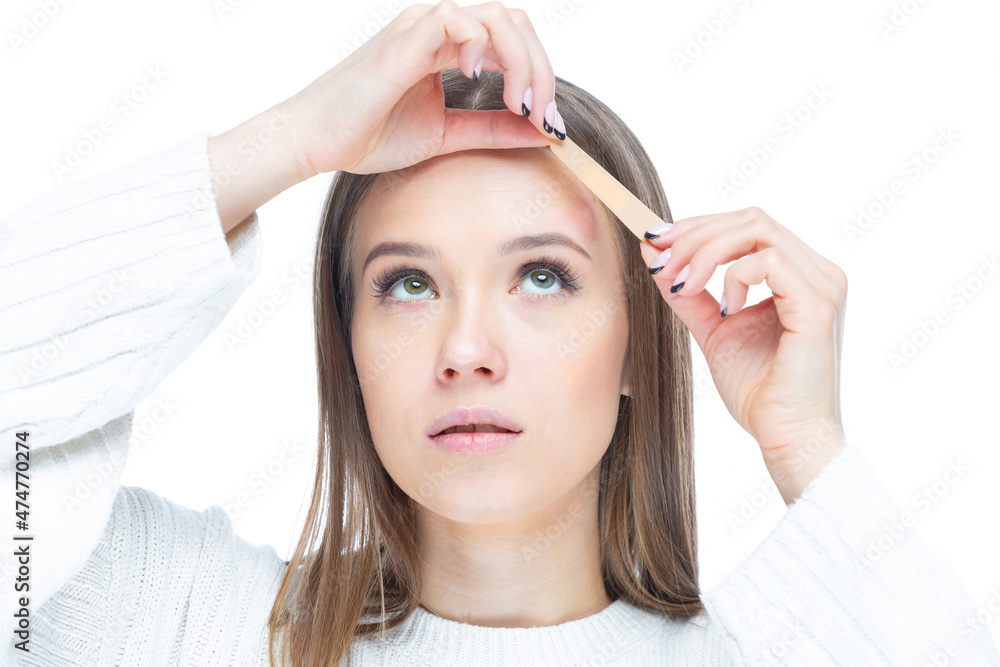 Naklejka premium Close up shot of young sad woman applying adhesive bandage on her forehead after injury isolated on white background