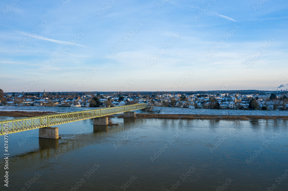 The pedestrian bridge of Sully sur Loire under the snow in Europe, in France, in the Center region, in the Loiret, towards Orleans, in Winter, during a sunny day.