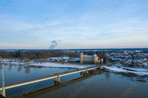 The Sully sur Loire bridge and its town center under the snow in Europe, in France, in the Center region, in the Loiret, towards Orleans, in Winter, on a sunny day.