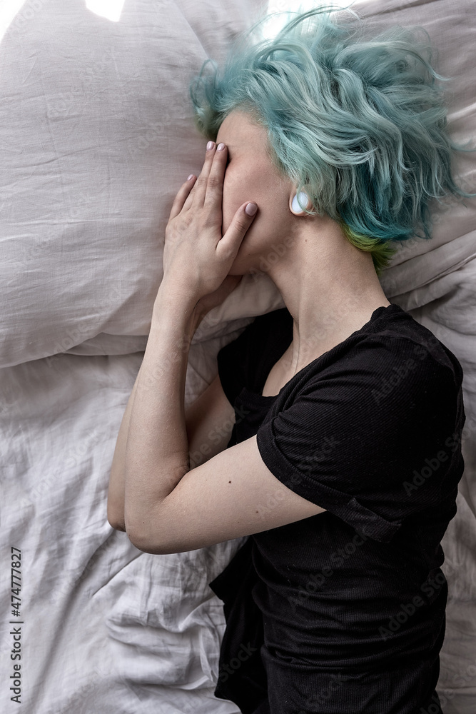 top view on stressed sad young woman lying on bed looking desperate