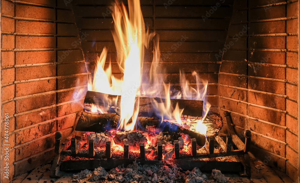 Christmas time, cozy fireplace. Wood logs burning, fire bricks background, relaxation and warm home.