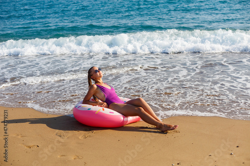 Woman on vacation on the beach relaxing in an inflatable ring on the ocean beach in travel. Girl in a swimsuit on the seashore in Turkey