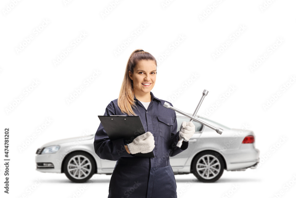 Female auto mechanic holding a lug wrench in front of a silver car Female auto mechanic holding a lug wrench in front of a silver car