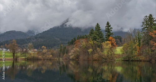 Time lapse of motion lapse view of pristine small lake. Clouds covering mountains peaks. Amazing and pristine nature in autumn season. Pond Crnava, Preddvor, Slovenia. Colorful or vibrant landscape photo