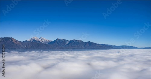 Time lapse of cloud inversion or temperature inversion. Thick layer of mist clinging to the ground in Slovenia. Sea of cloud with mountain tops rising out of the fog. Aerial or elevated view. Static