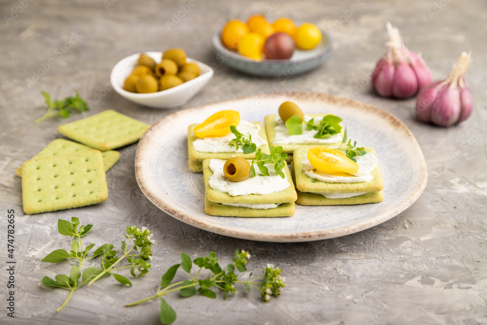 Green cracker sandwiches with cream cheese and tomatoes on gray concrete background. side view, close up. Green cracker sandwiches with cream cheese and tomatoes on gray concrete background. side view, close up.