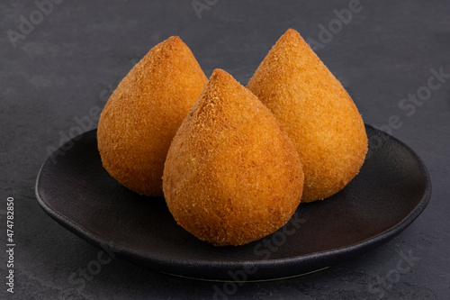 traditional fried coxinha on a black plate on a slate background - brazilian snack photo