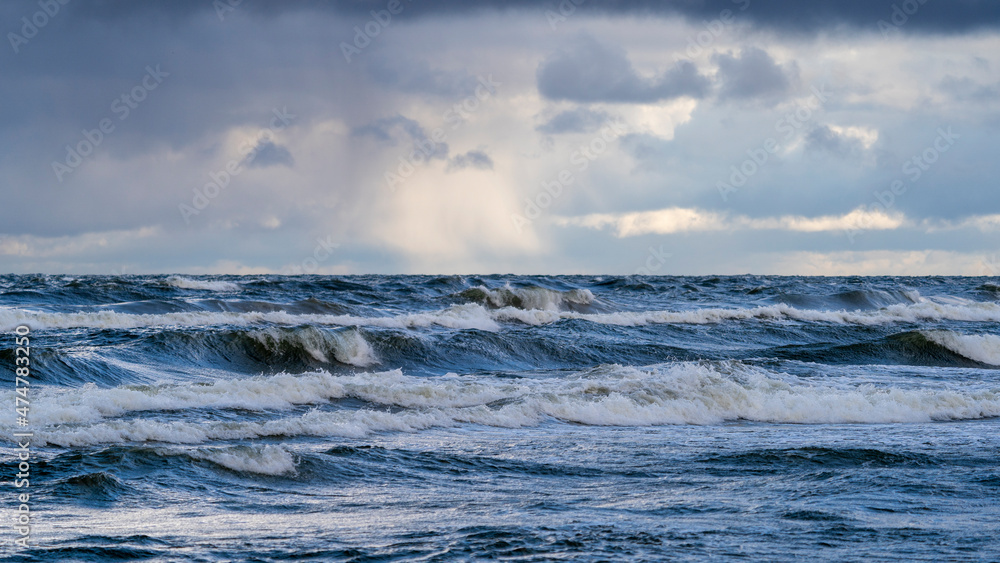 Piękny widok wzburzonego morza na tle promieni 
 słońca przebijających się przez ciężkie chmury (Morze Bałtyckie) - obrazy, fototapety, plakaty 