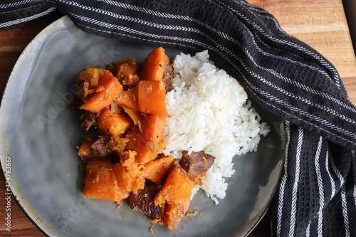 A plate of pumpkin bredie. Traditional South African dish made with pumpkin or butternut squash chunks and meat. Cinnamon sticks. Jasmine rice photo