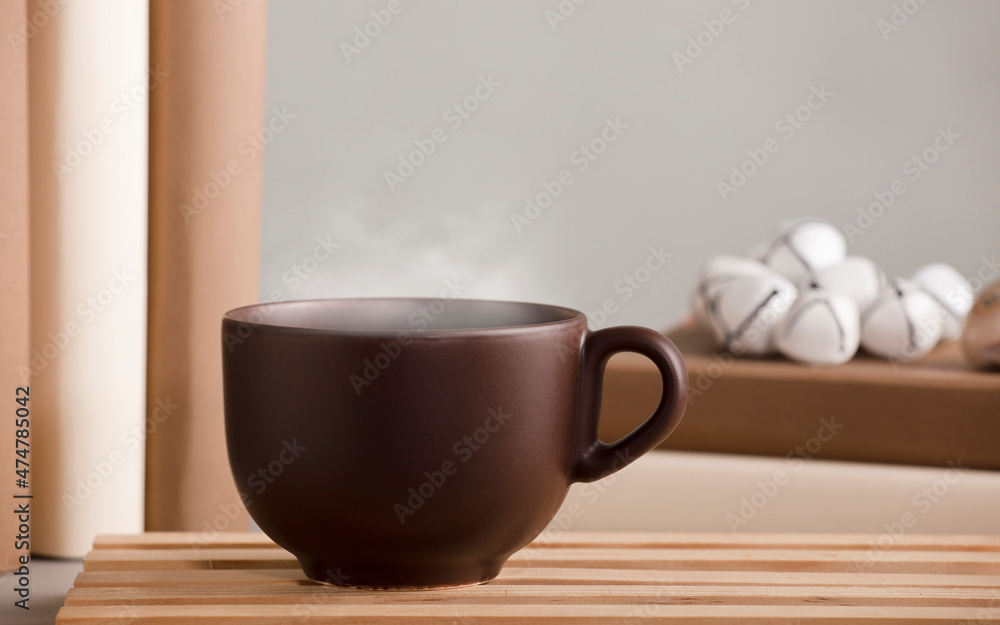 white cup of coffee with hot steam, on the desk with shells and books, grey background white cup of coffee with hot steam, on the desk with shells and books, grey background