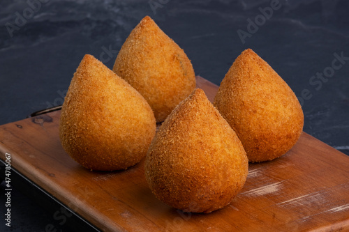 traditional fried coxinha on a wooden board over slate stone