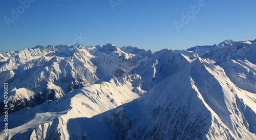 survol, vue d'avion d'une superbe chaine montagneuse enneigé sous le soleil avec un ciel bleu  © pj69