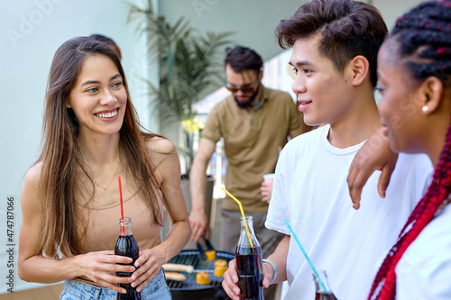 International group of young people in casual wear have talk, fun during party outdoors. Attractive caucasian african and chinese friends students drinking beverages, smiling, laughing. portrait
