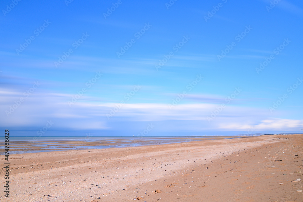 Clouds moving over the Channel Sea and the sandy beach in Europe, France, Normandy, Ouistreham, in summer on a sunny day.