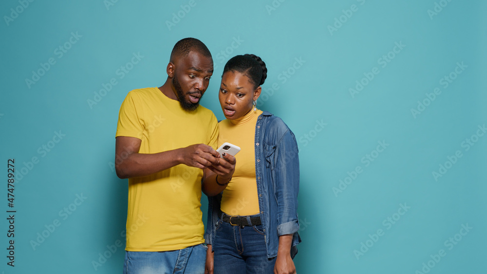 Man and woman using internet on smartphone together in front of camera. People looking at mobile phone display and having positive connection. Modern couple working with technology. Man and woman using internet on smartphone together in front of camera. People looking at mobile phone display and having positive connection. Modern couple working with technology.