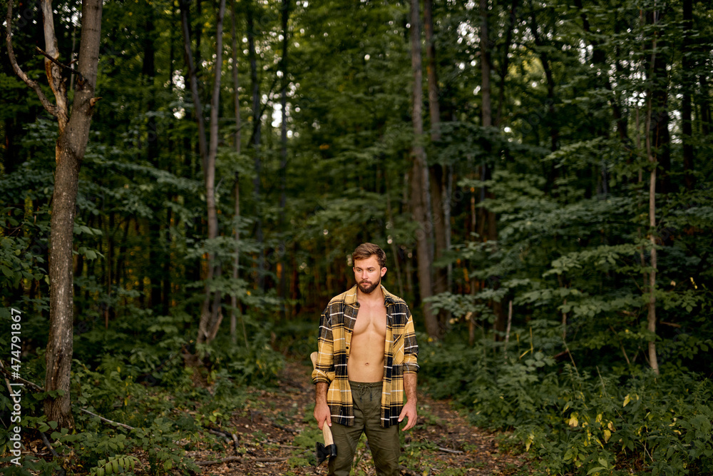 Logging season. Confident Caucasian Lumberman carry axe in forest, sexy handsome woodman. Forestry logging. Chopping wood. Summer nature. Natural landscape. Ecology and environment. Lumberjack