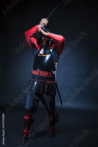 A man in samurai armor holds a sword over his head