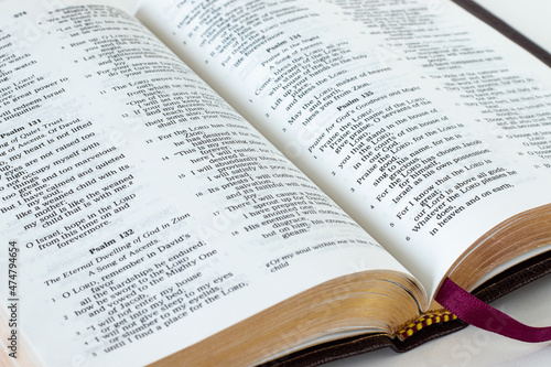 Close-up of open Holy Bible Book with gold pages. Studying Old Testament Psalms. A biblical concept of worship, praise, and praying to God Jesus Christ. Inspiring Scripture verses.