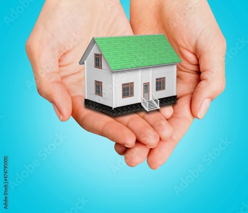 Wooden house miniature in hand on background