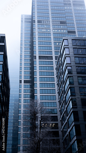 Business center in the tower skyscraper in the financial downtown center of the city in the foggy misty day with cover by clouds tops. Financial business abstract architecture concept.