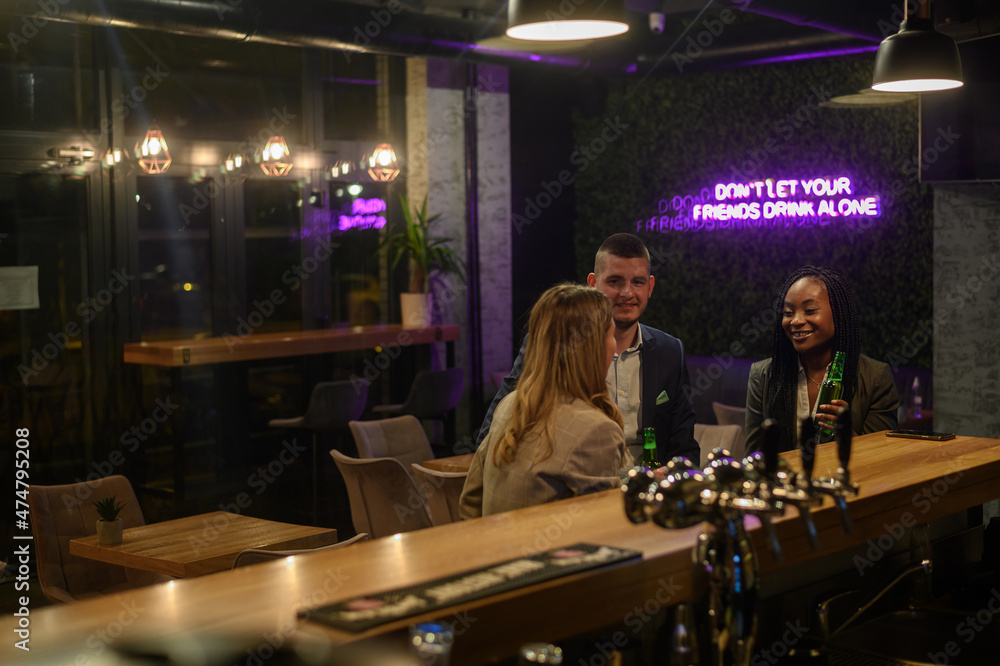 Cheerful colleagues drinking beer in the bar together after work