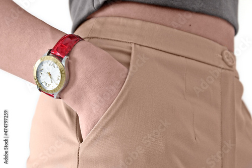 A close-up female figure in beige trousers confidently stands sideways, holding her hand in the pockets of her trousers. I have an expensive watch on my hands. Concept: business woman, technology..