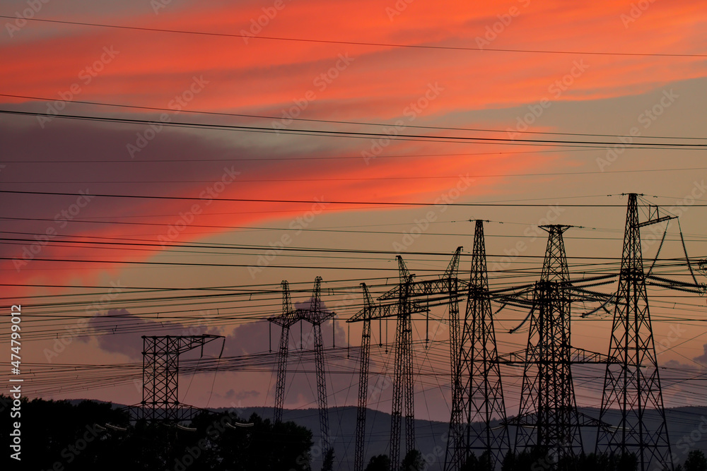 Russia. Krasnoyarsk Territory. The interweaving of electrical poles and wires against the background of a flaming red sunset near the power plant in the city of Sharypovo.