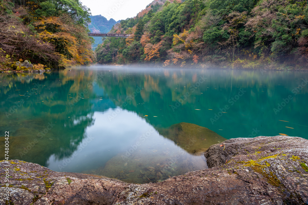 Autumn landscape beautiful colour trees over the river glowing in the sunlight and misty. wonderful background. mountain reflection green water. Amazing view river dam in Japan Autumn landscape beautiful colour trees over the river glowing in the sunlight and misty. wonderful background. mountain reflection green water. Amazing view river dam in Japan